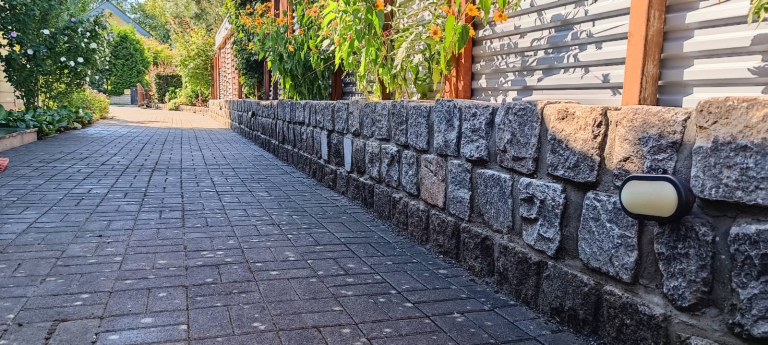 Gepflasterter Gartenweg entlang einer niedrigen Steinmauer